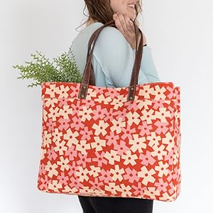 A woman holds up a MAIKA Carryall Tote in the Solvang pattern.