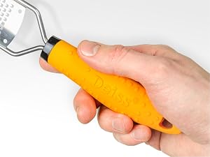 Orange ergonomic handle grip shown in use, attached to a metal tool or utensil, with textured surface for improved grip control.