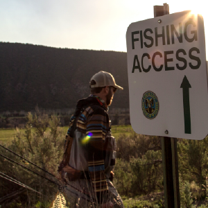 man walking next to fishing access sign