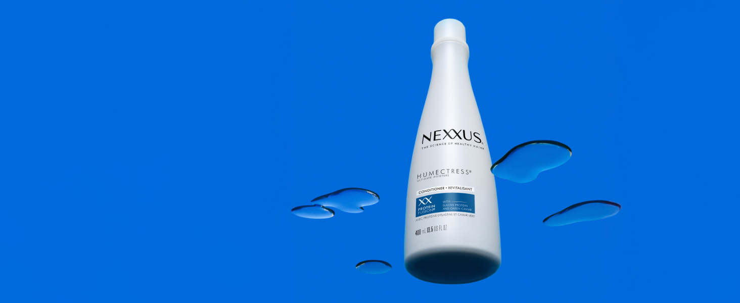 Nexxus conditioner bottle on a glass surface with some water.