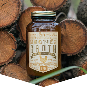 EPIC chicken bone broth jar standing on chopped wood logs