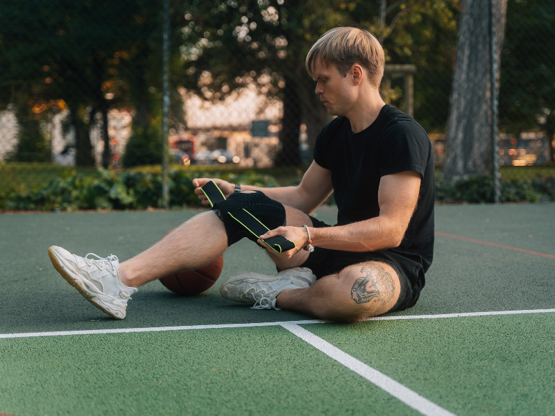Man sitting down adjusting the BODYPROX Knee Brace with Side Stabilizers