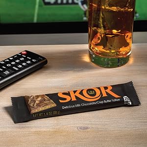 Packaged Skor candy bar near a television remote and a drink