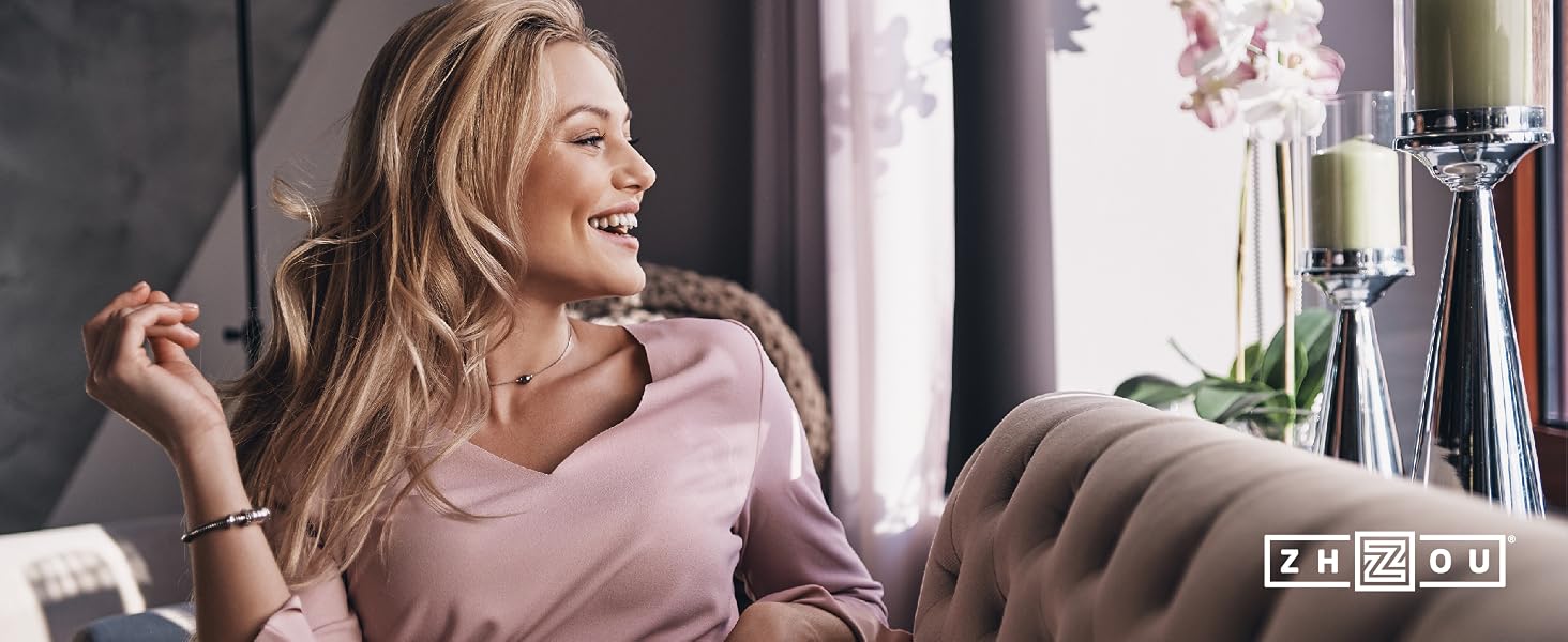 woman looking out sunny window while sitting on a couch smiling