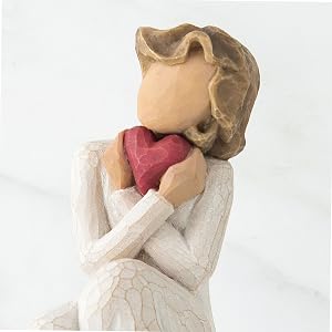 Close up detail of figure holding heart to face.