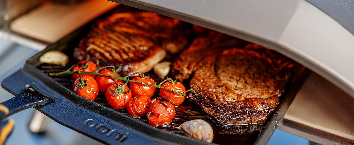 a grill with meat and tomatoes cooking in it