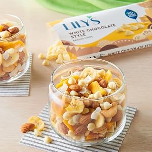 A bag of Lily's white chocolate style baking chips open and placed behind cups of trail mix