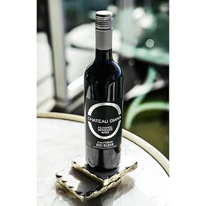 A bottle of Chateau Diana Alcohol-Removed California Red Blend on stone coasters on a table.