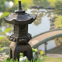 A lush Asian-inspired garden with a calm reflective pond, water lilies floating on the surface, weep