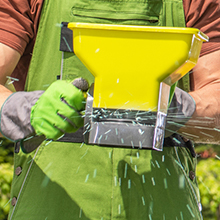Gloved hand using manual granular spreader
