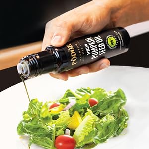 pouring pödör styrian pumpkin seed oil into salad