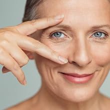 mature woman smiling and featuring eye with hand.