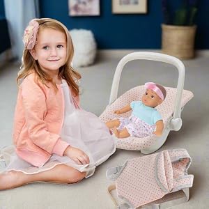 a young girl sitting on the ground next to the car seat and baby carrier