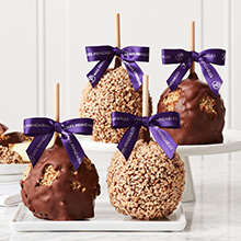 Four Caramel Apples, Milk Chocolate Walnut and Toffee Walnut flavored, are topped with purple bows