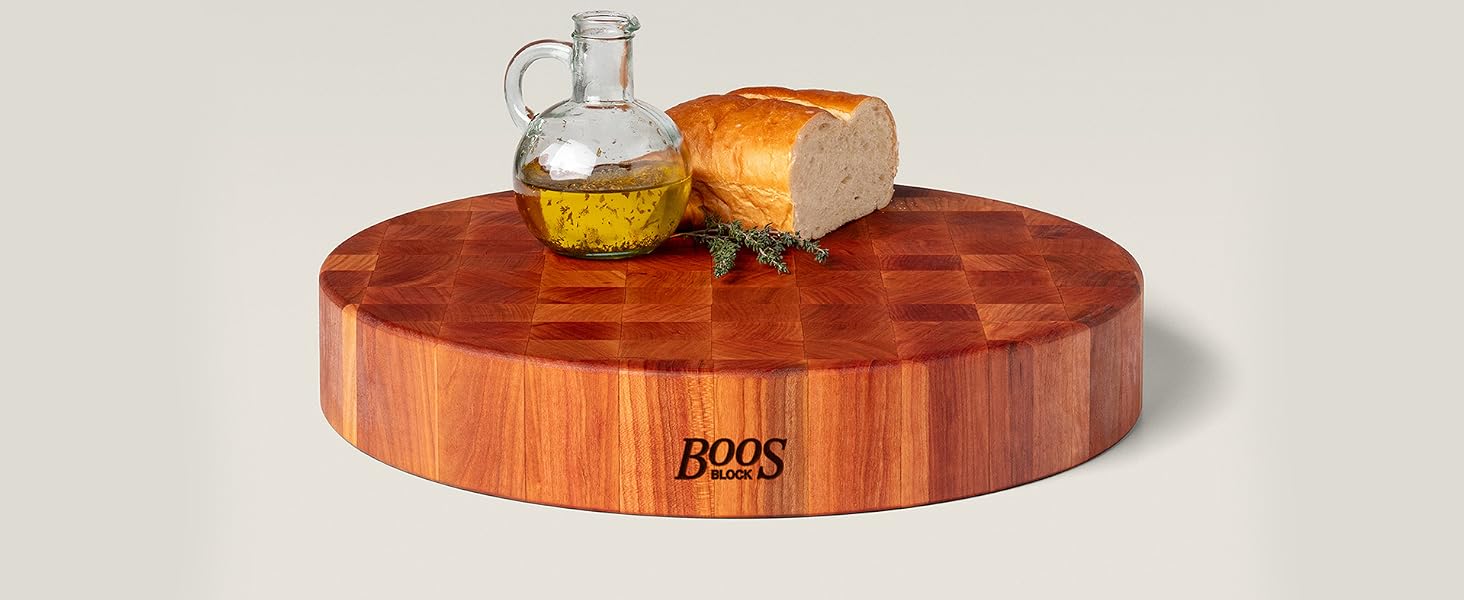 A bottle of olive oil and bread on a wooden chopping block on light background.