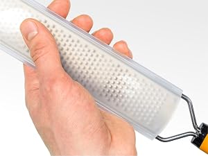 Close-up of a hand holding a transparent plastic foot file with raised dots for exfoliation. Metal handle visible at one end.