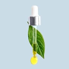 eye dropper with tea tree oil in front of a tea tree leaf on a light blue background.
