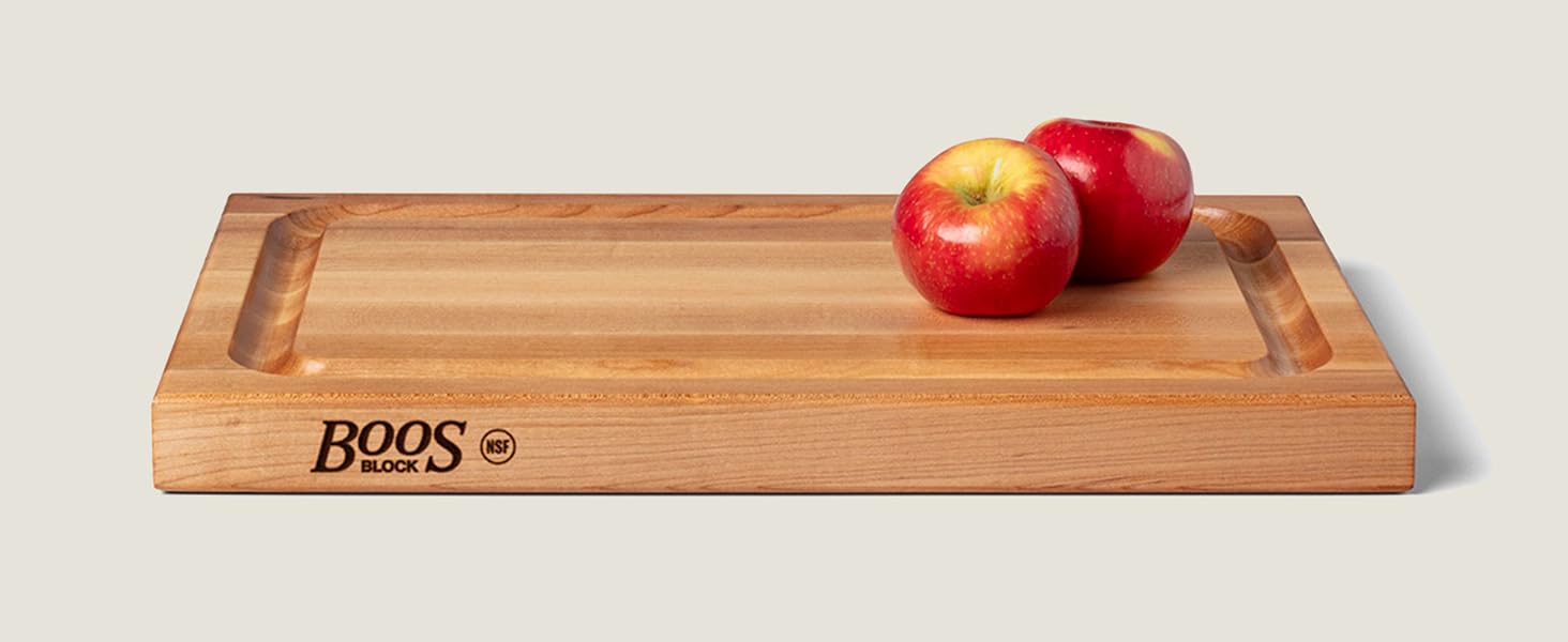 Wood cutting board with apples placed on top, showcasing smooth finish and rich grain.