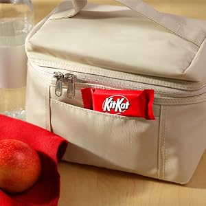 A snack size Kit Kat candy bar poking out of a lunch box, alongside an apple and a water bottle
