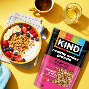 Person holding KIND Breakfast Bar in one hand and coffee in the other