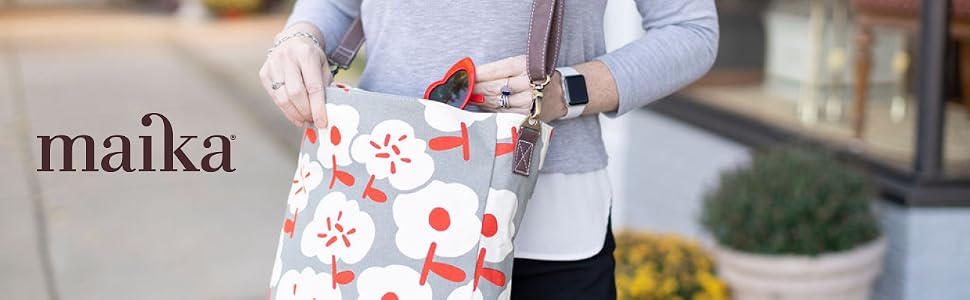 A person wearing the MAIKA Crossbody bag pulls a pair of red sunglasses out of the bag.