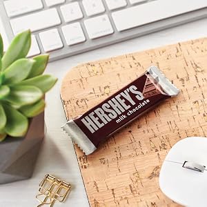 Snack size Hershey's milk chocolate candy bar on a desk next to a desk plant, mouse, and keyboard