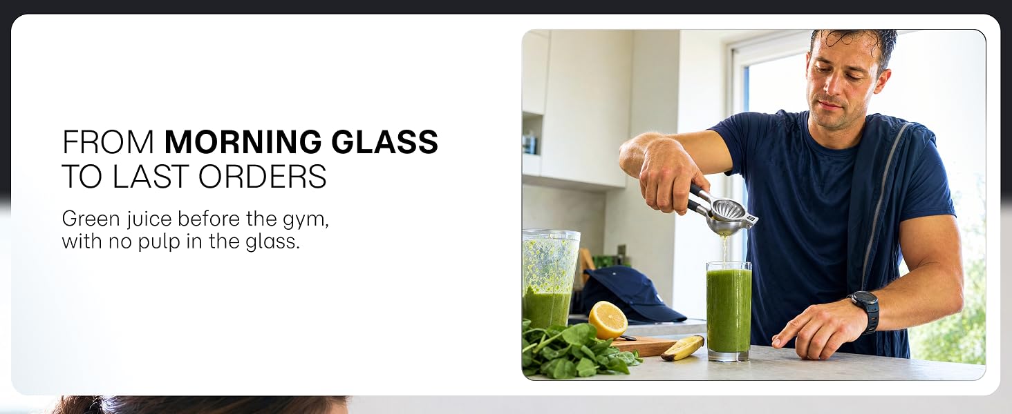 A man squeezes a lemon into his green smoothie with a handheld stainless steel citrus juicer.
