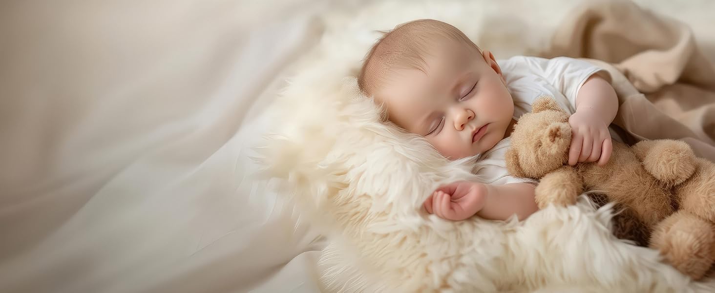 Sleeping baby cuddled on soft lambskin baby rug with teddy bear