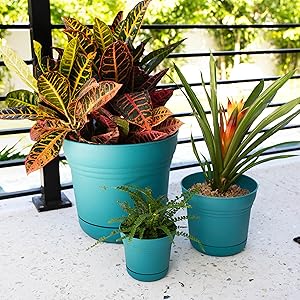 image of three saturn planters in bermuda teal on the floor against a railing