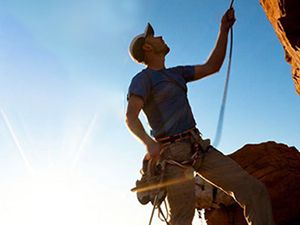 Man climbing mountain and using Avantree Cyclone speaker to listen to music.