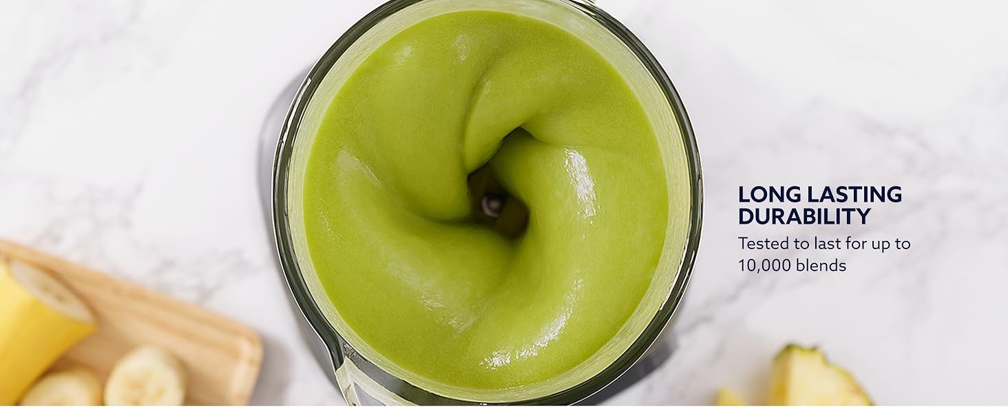 Overhead view of green smoothie spinning in blender jar with bananas nearby