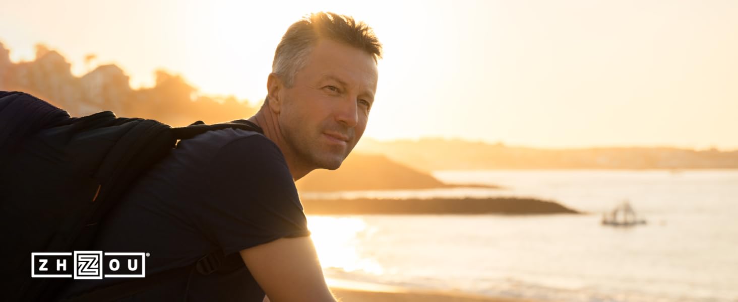 Healthy middle aged man watching the sunset over the ocean after a hike.