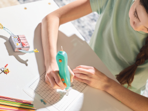 Girl overhead view with a 3Doodler Start+ 3D printing pen and mat.