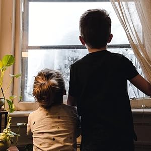 2 children looking out the window for birds.