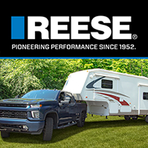 Chevy pickup truck towing a 5th wheel RV trailer with a goose box and the REESE logo above it