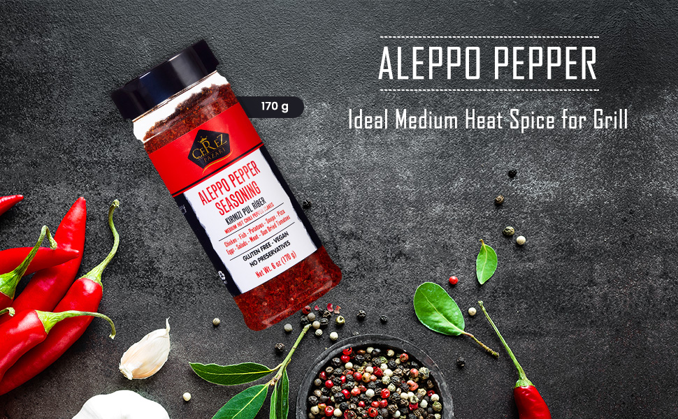 Text reads 'ALEPPO PEPPER' and 'Ideal Medium Heat Spice for Grill'. Dark background with red peppers, garlic, herbs, and peppercorns arranged artistically.