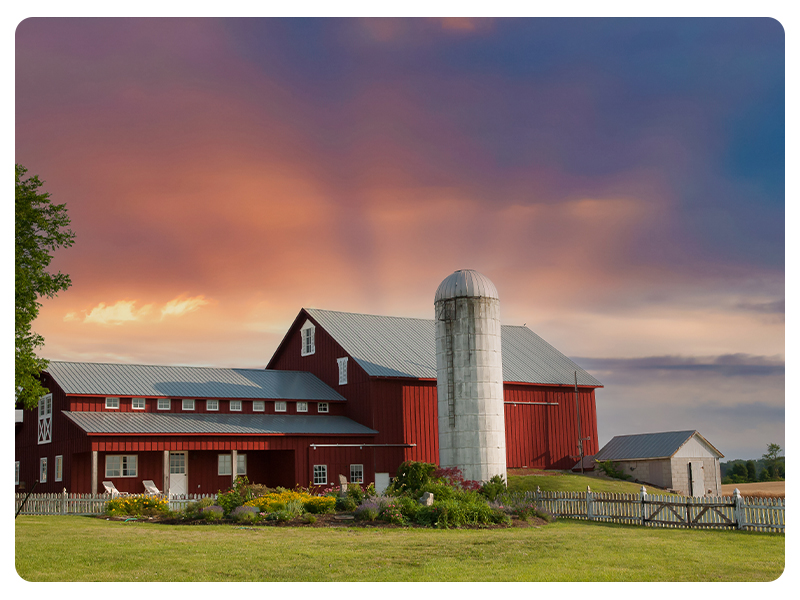 a red barn with the sun setting behind it