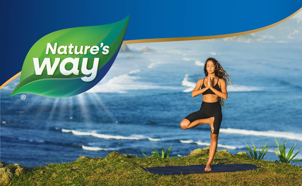 Woman doing yoga on cliff above blue ocean.