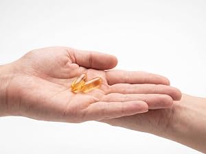 Two golden MCT oil softgels held in an open hand
