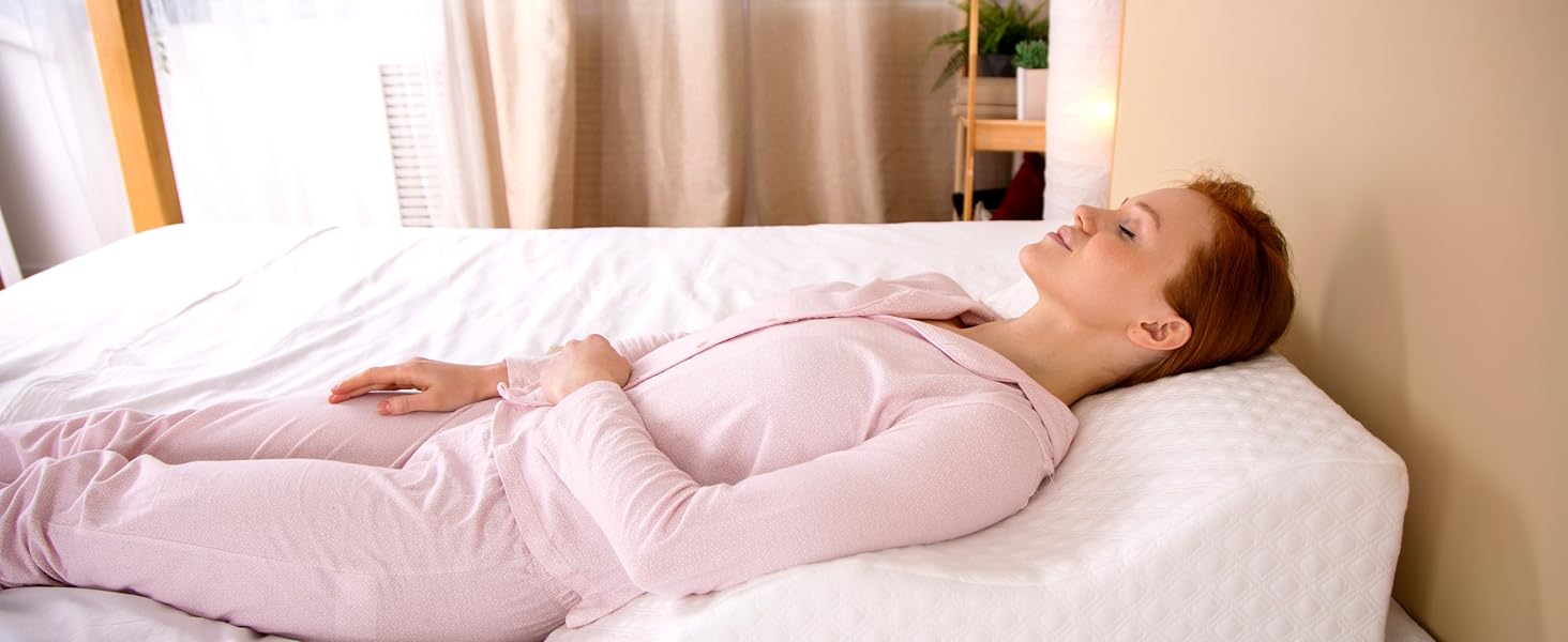Calm bedroom scene with person resting elevated on wedge pillow.