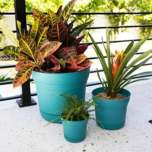 image of three saturn planters in bermuda teal on the floor against a railing