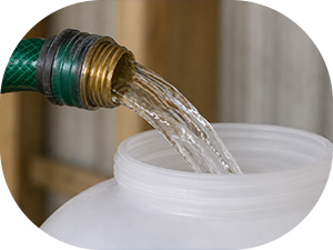 refilling a plastic hanging chicken waterer with a garden hose