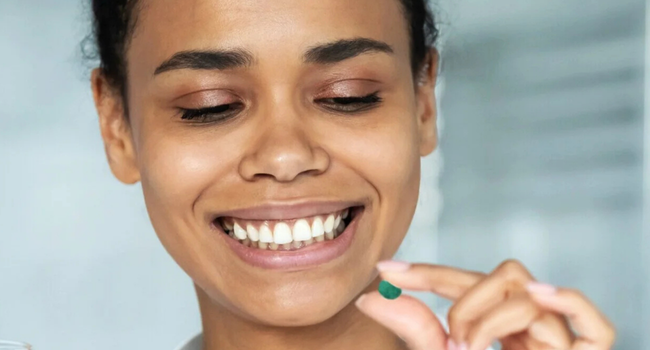 Person holding an Earthrise spirulina tablet before taking it.