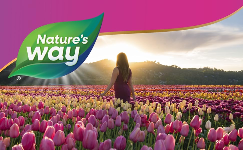 Woman walking through field of pink and yellow tulips.
