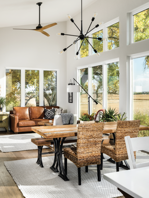 An open living room with fans, dining table, and couch with large windows