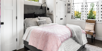 A cozy white bedroom with bed, lamp, chair, and closet