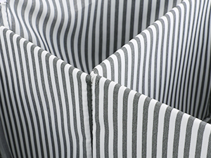Close-up of black and white vertical striped fabric showing crisp pleats or folds creating a geometric pattern.