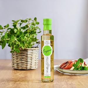 Messino White Wine Vinegar with Oregano bottle next to caprese salad and basil plant