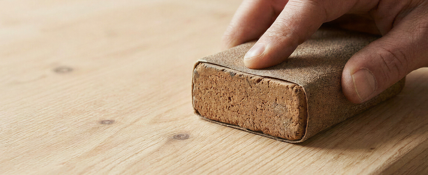 Hand pressing or cleaning a cork block against wooden surface