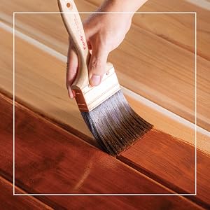 painter brushing on light brown stain on wood
